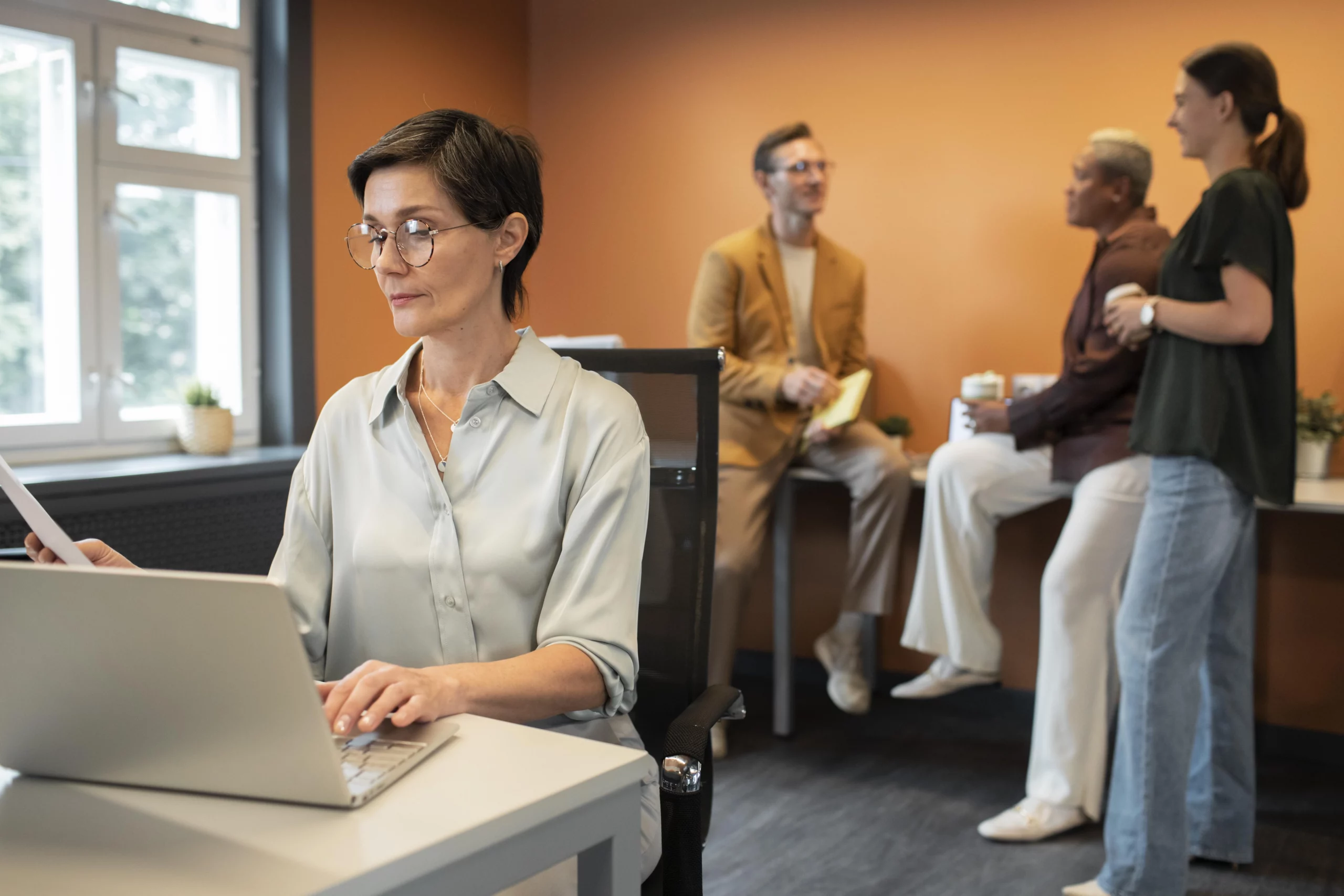 Groupe de professionnels en pleine conversation dans un bureau moderne, préparant leur certification Qualiopi à Grenoble