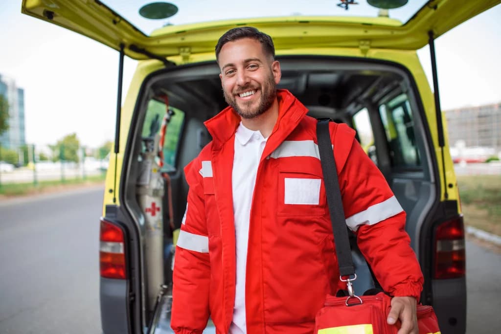 Secouriste souriant en tenue professionnelle devant une ambulance, symbole de la formation Qualiopi en secourisme.